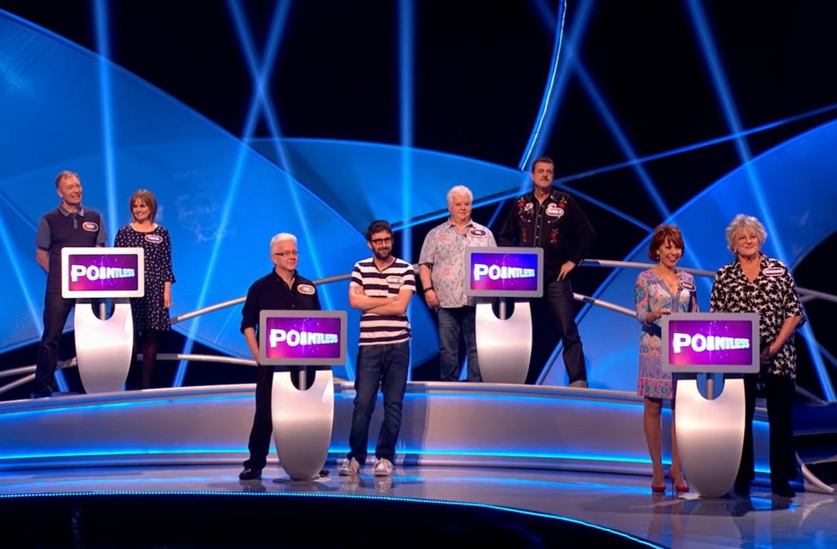 Pointless contestants stood at podiums.