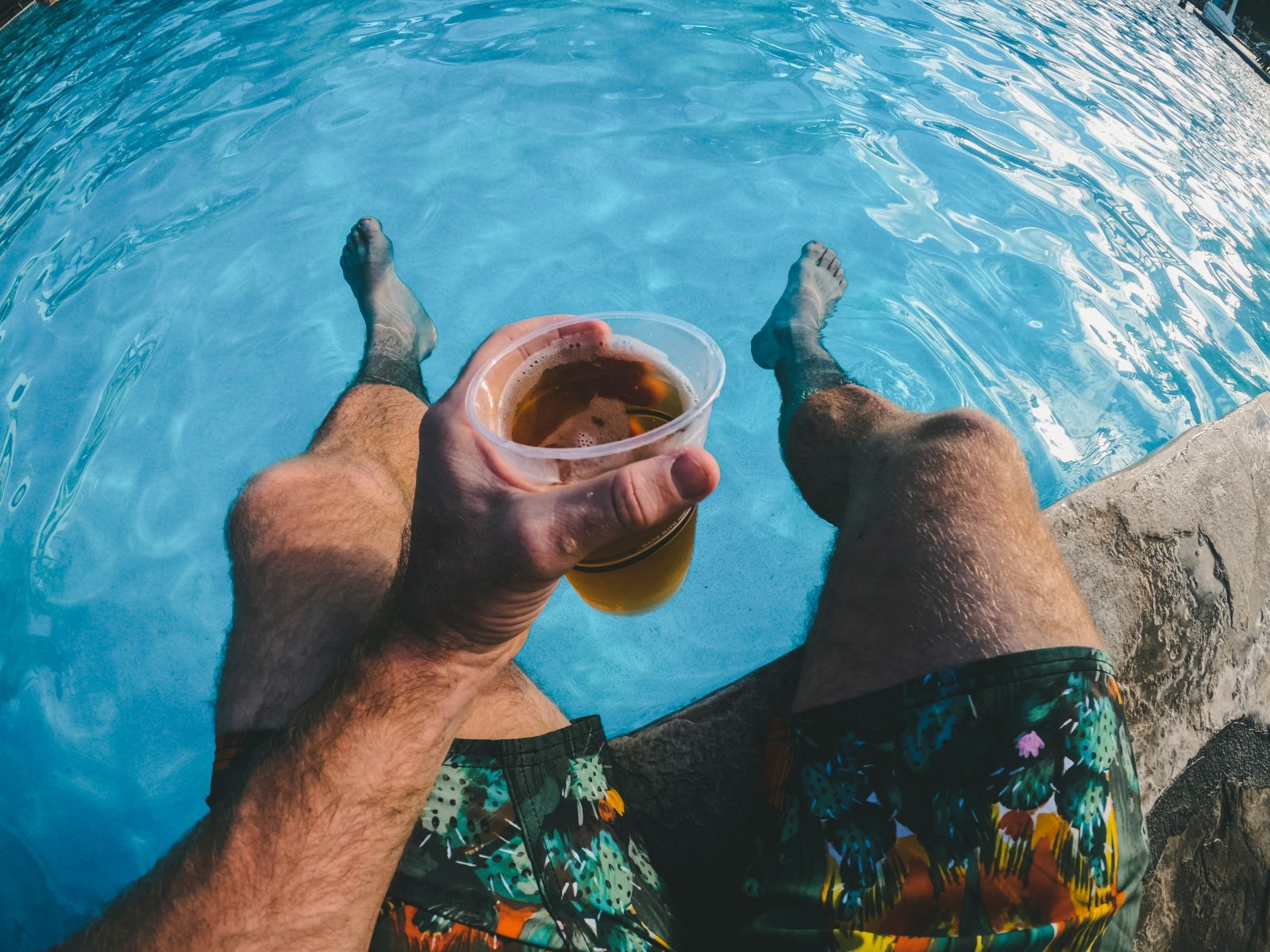 man holding beer in pool.
