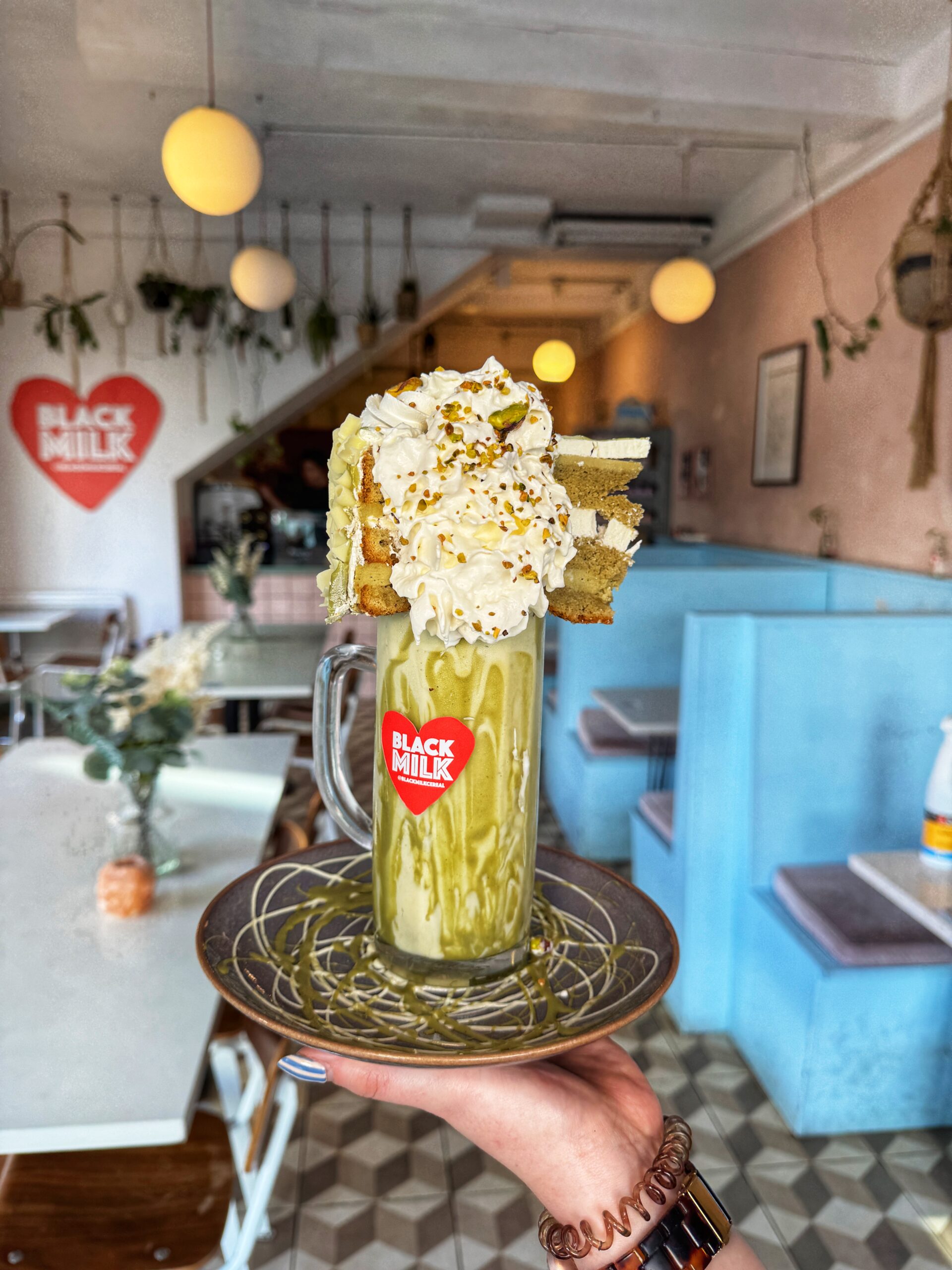 A pistachio milkshake with pistachio cake on top at Black Milk