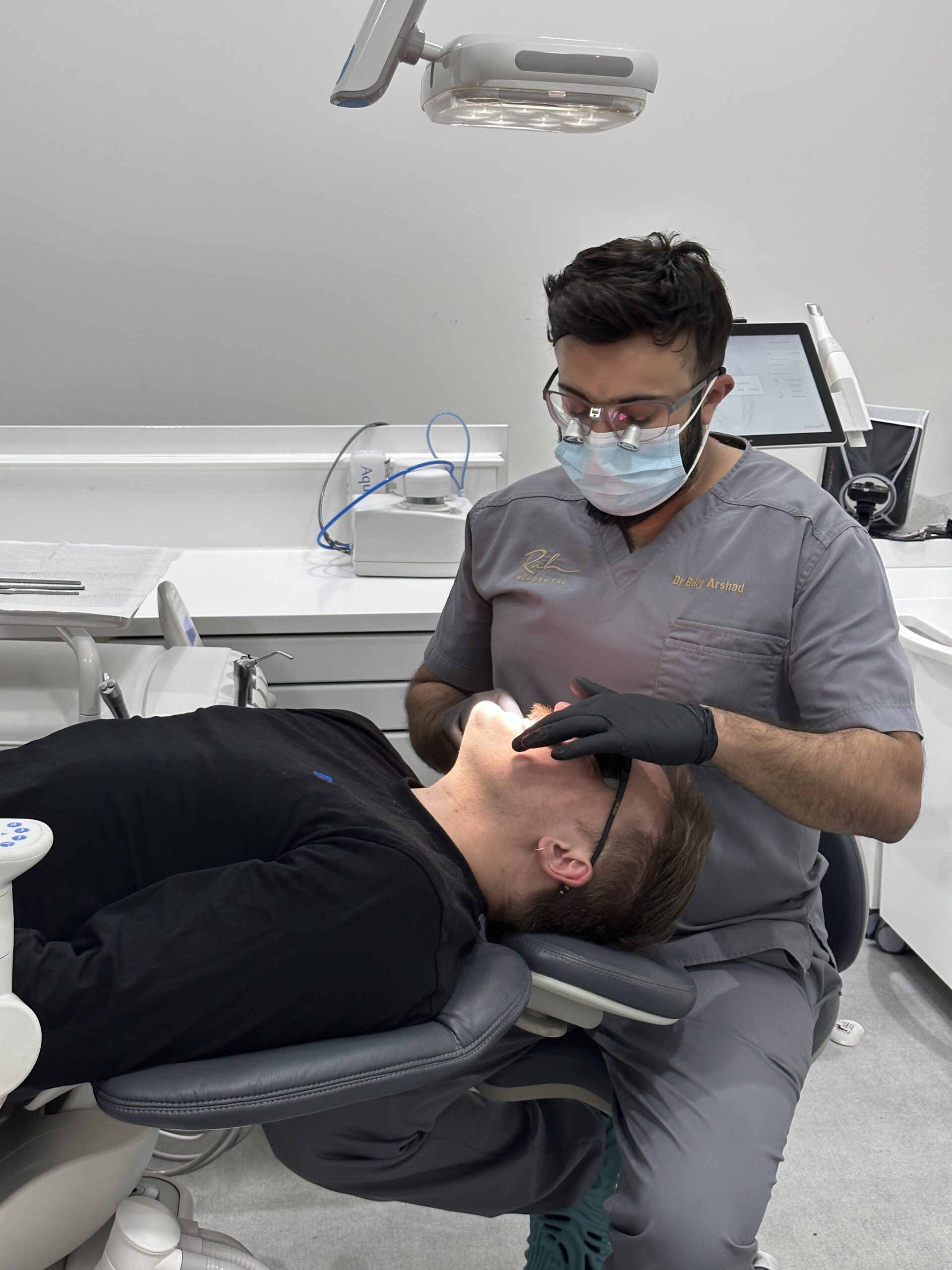 Dr Bilal taking a look at Kris' teeth during an appointment at Rüh Dental.